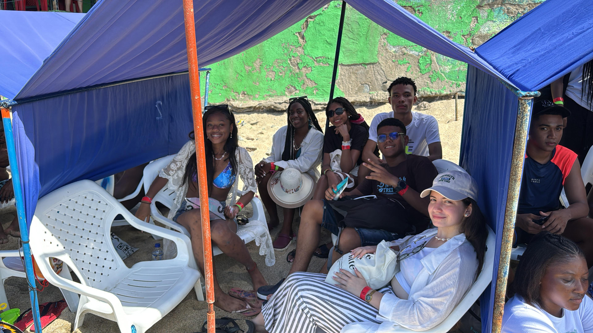 Viajeros descansando bajo carpas azules en la playa durante la excursión a Santa Marta 2024