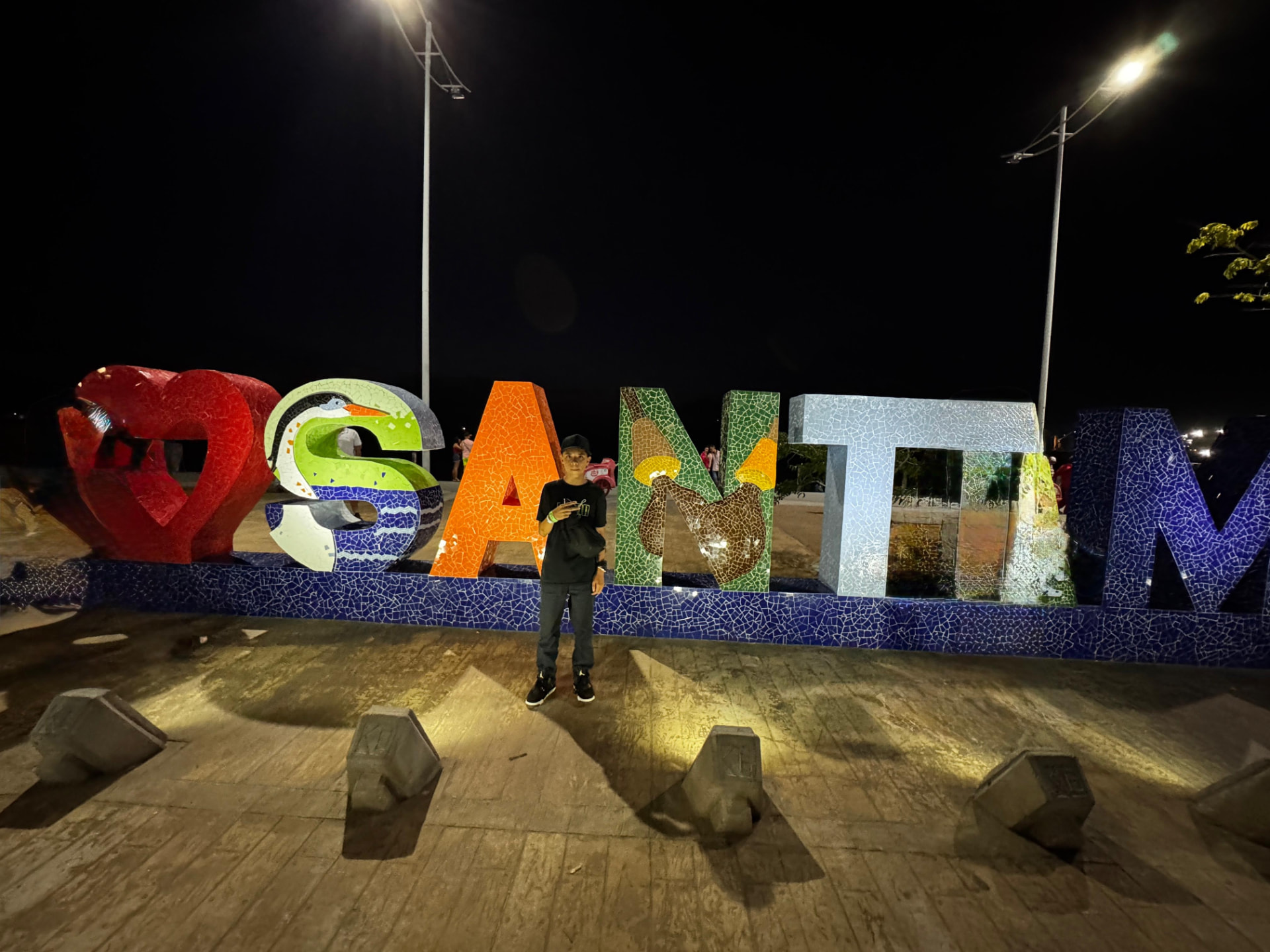 Viajero posando de noche frente al letrero turístico de Santa Marta, 2024