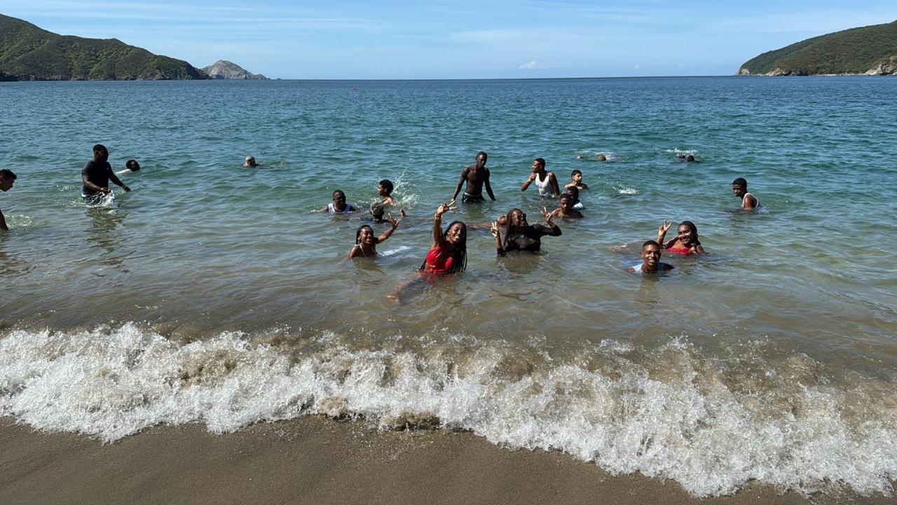 Grupo de jóvenes bañándose en el mar rodeado de montañas, Santa Marta 2025